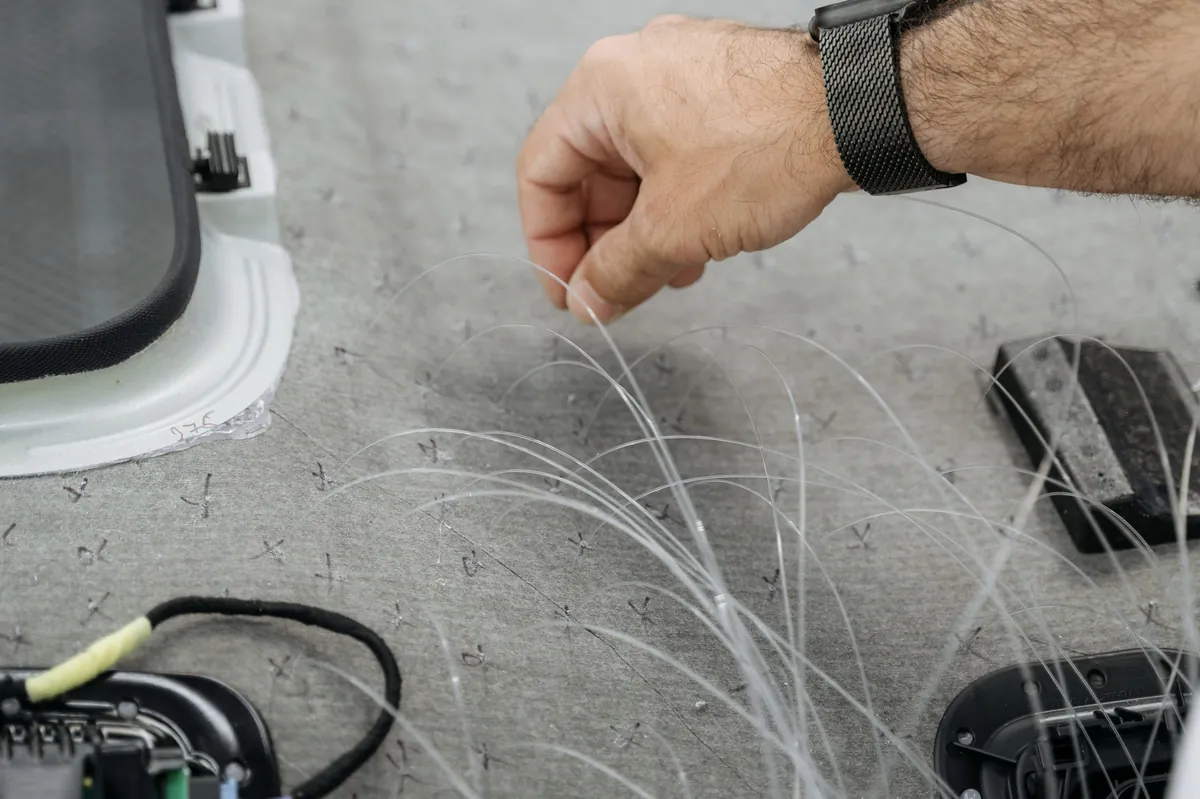 Fibre-optic strands being routed through the Porsche Macan headliner foam backing during starlight install